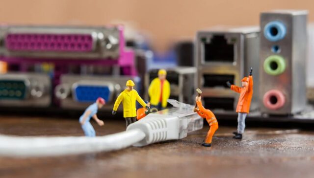 Miniature workers managing computer cables and connectors.