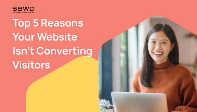 Smiling woman with laptop in a digital agency's creative workspace.